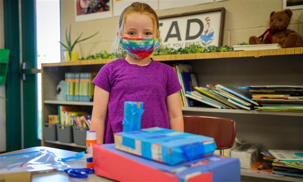 Student holds up a castle made out of recycled materials